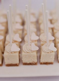 small desserts with white frosting and heart shaped candles are arranged on a plate