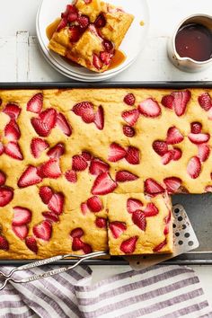 a cake with strawberries on it is sitting on a pan and next to two plates