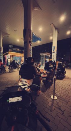 people are sitting on motorcycles at the gas station