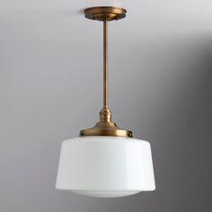 a light fixture with a white shade hanging from it's side on a gray wall