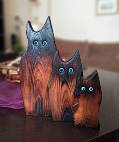 two wooden cats with blue eyes sitting on a table