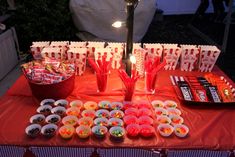 a table topped with lots of candy and candies next to a lamp post on top of a red cloth covered table