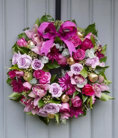 a wreath with pink and purple flowers hanging on a door