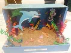 an open box with sea animals and fish in it on a white tablecloth covered surface