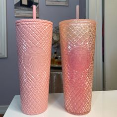 two pink tumblers sitting on top of a counter