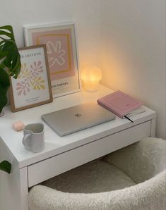 a white desk with a laptop on it and a potted plant next to it