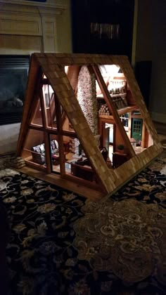 a wooden structure sitting on top of a rug in front of a fire place and fireplace