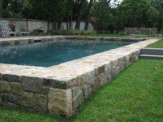 a pool surrounded by stone walls and grass