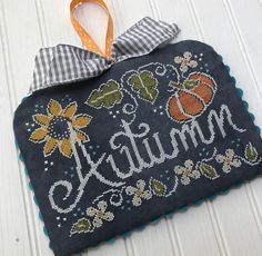 a cross stitch ornament hanging on the side of a wall with a ribbon