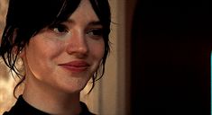 a close up of a person wearing a black shirt and looking at the camera with a smile on her face