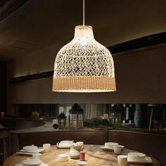 a wooden table topped with white plates and bowls under a light hanging from the ceiling