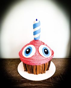 a cupcake with eyes and a candle on top