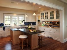 a large kitchen with white cabinets and black counter tops is pictured in this image, there are two stools at the center of the island