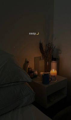 a lit candle on a night stand next to a bed