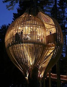 a large wooden structure with lights on it's sides and people inside at the top