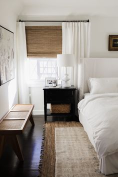 a bedroom with white bedding and curtains