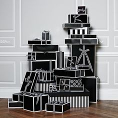 a stack of black and white boxes sitting on top of a wooden floor next to a wall