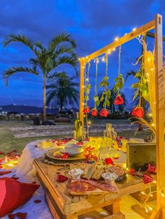 a wooden table topped with lots of food under a sky filled with stars and lights