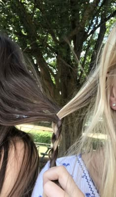 two women with long hair and one is cutting the other's hair