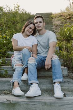 a man and woman are sitting on some steps smiling at the camera with their arms around each other