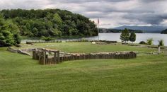 a large grassy field next to a body of water