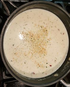 a pan filled with soup sitting on top of a stovetop next to silver spoons