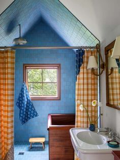 a bathroom with blue and orange tiles on the walls, shower curtain, sink and mirror