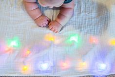 a baby laying on top of a blanket with lights all over it's body