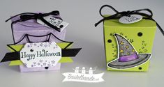 two small boxes with tags on them are sitting side by side, one has a witches hat and the other has a happy halloween tag