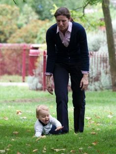 a woman is playing with a baby in the grass and another person is standing next to her