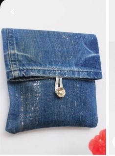 a small denim pouch with a heart charm hanging from it's front pocket, next to a red flower