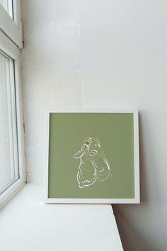 a white frame sitting on top of a window sill next to a green wall