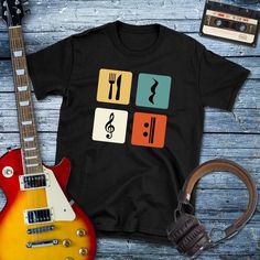 an electric guitar, headphones, and t - shirt on a wooden table