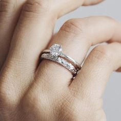 a woman's hand with a diamond ring on her left hand and the other hand holding it