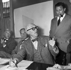 black and white photograph of men in suits sitting around a table with papers on it