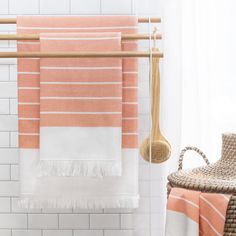 two towels hanging on a towel rack next to a wicker chair and woven basket