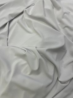 an unmade bed with white sheets and pillows