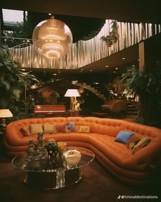 an orange couch sitting in the middle of a living room next to a glass table