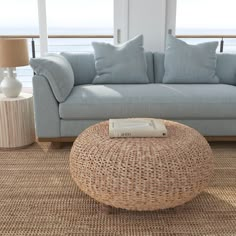 a living room with a wicker coffee table and blue couch in front of the window