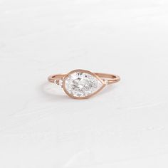 a pear shaped diamond ring on a white surface