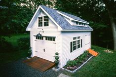 a small white house sitting on top of a lush green field