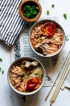 several plates of food on a table with chopsticks in the middle and two people holding chop sticks above them