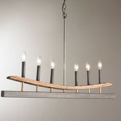 a chandelier with six lit candles hanging from it's center beam and wooden plank