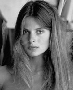 a black and white photo of a woman with long hair looking at the camera,