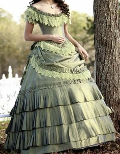 a woman in a green dress standing next to a tree