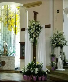 the altar is decorated with white flowers and greenery in purple vases on each side