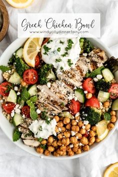 a white bowl filled with chicken, chickpeas, and cucumber salad