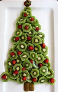 a christmas tree made out of kiwis and strawberries on a white plate