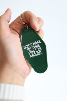 a hand holding a green keychain that says don't make me turn this year around