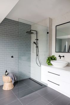 a modern bathroom with grey tile and white fixtures, including a walk - in shower